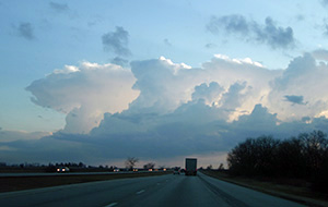 large cumulus clouds as seen while driving down a highway