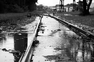 black and white image of train tracks and puddles